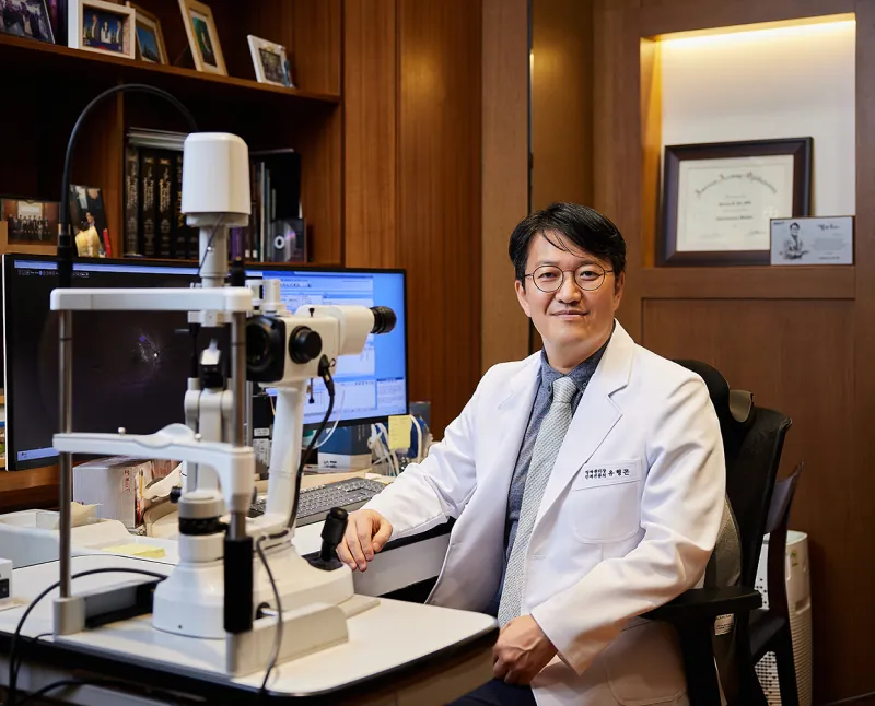 Retina specialist at Sky Eye Clinic seated beside a slit lamp in his consultation room in Seoul