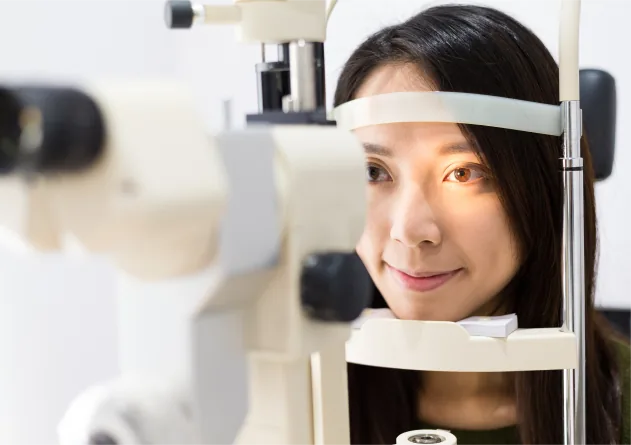 Woman placing her chin on a slit lamp during a pre-surgery eye examination
