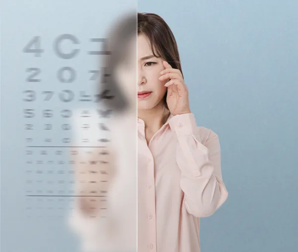 Woman rubbing her eye in front of a blurred eye chart, showing declining near vision